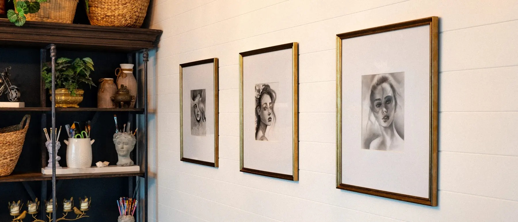 Framed charcoal portraits on the studio wall